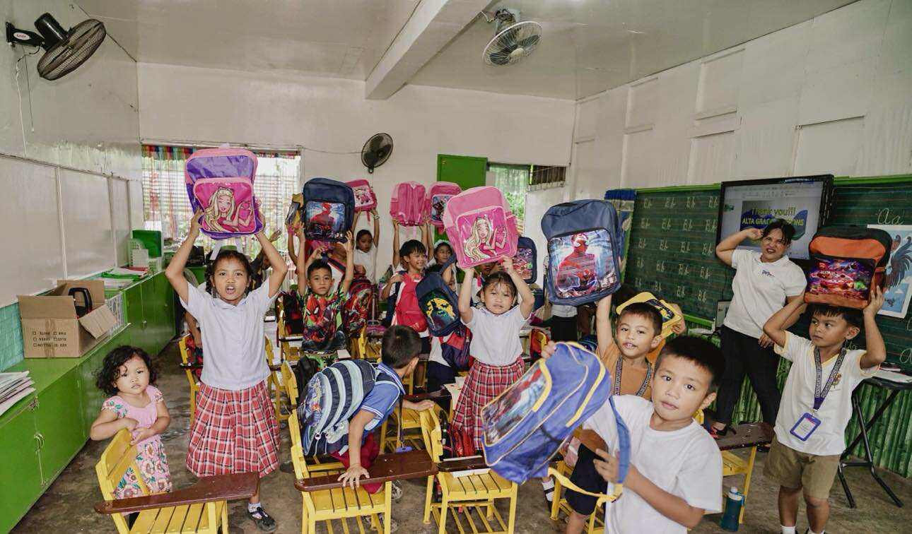 Children receiving school supply bags