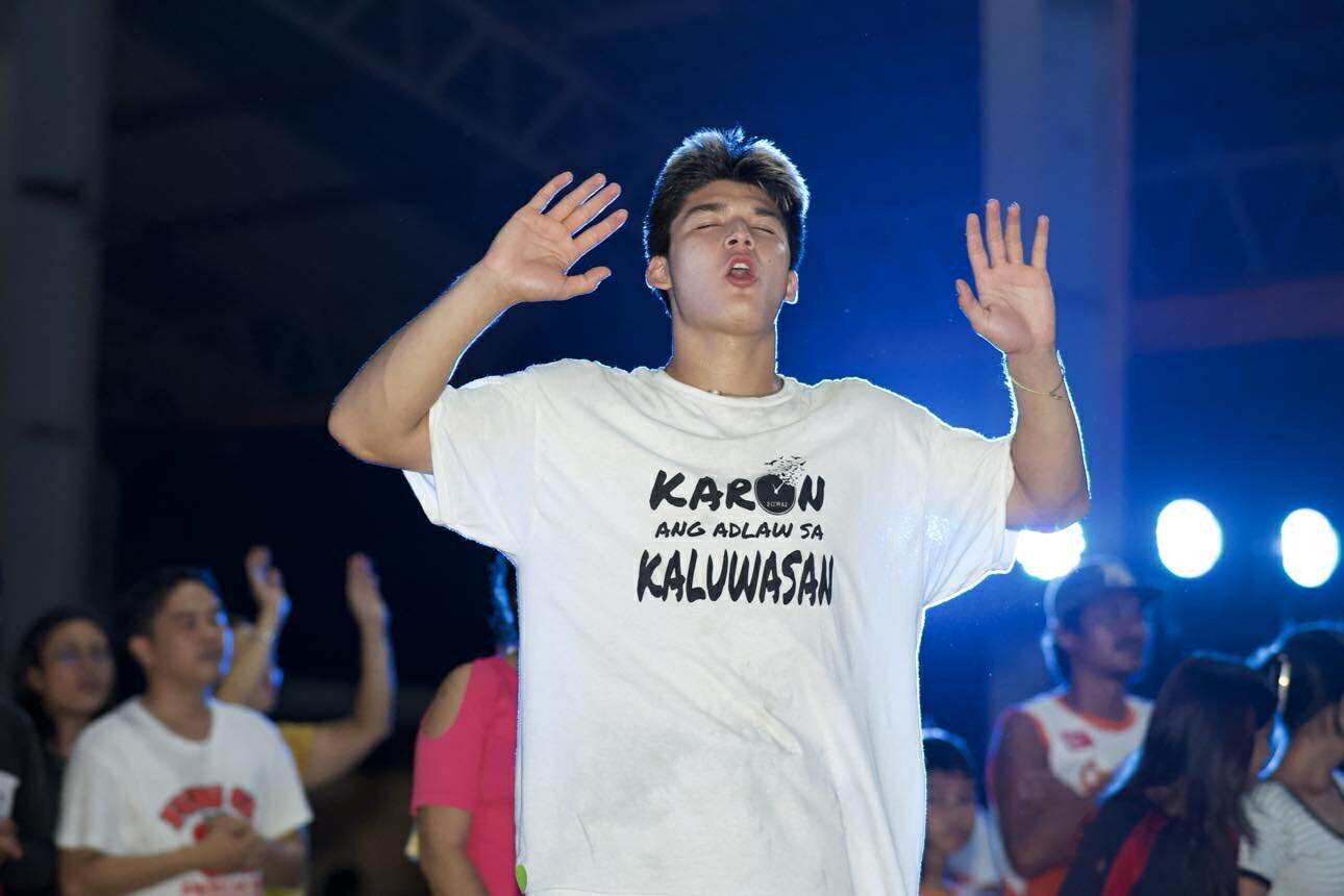 Young man worshipping under blue lights